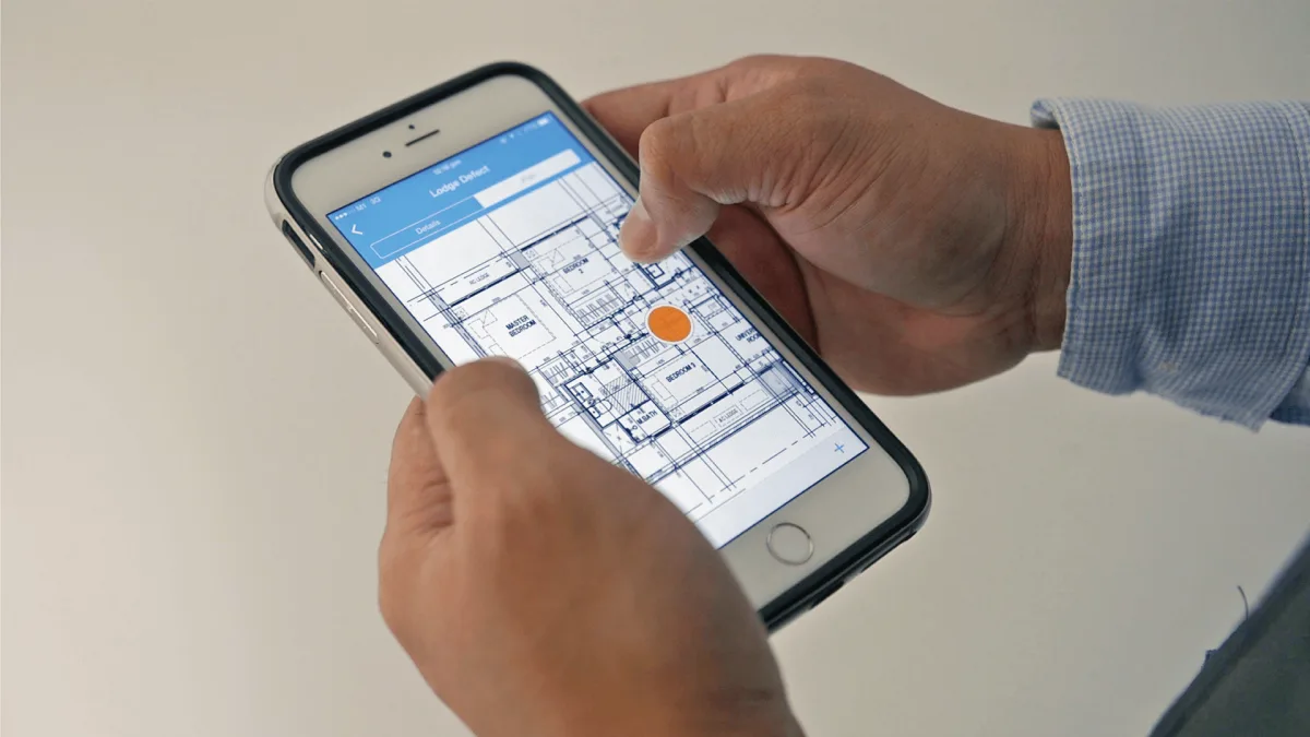 Site supervisor marking inspection point on construction blueprint using mobile app