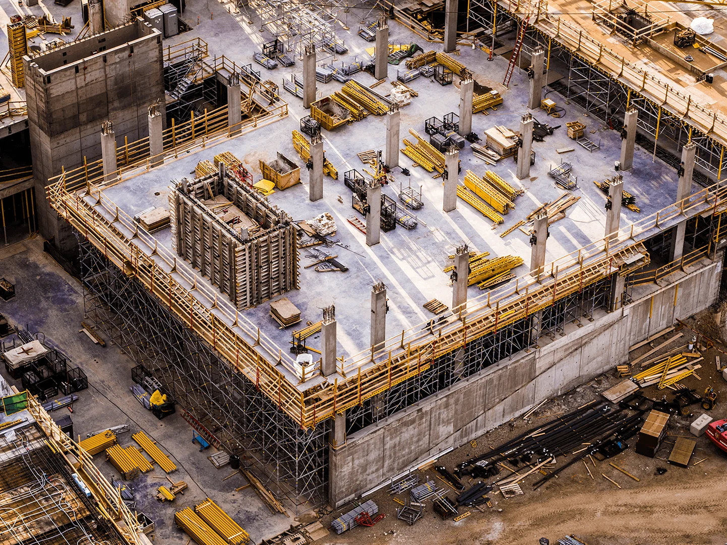 Aerial view of active construction site with concrete frame and safety scaffolding