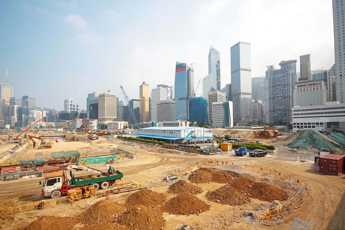 Large-scale construction site with excavation equipment and Hong Kong skyline