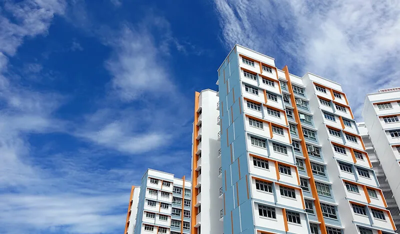 Modern social housing apartment complex with white facade and orange accents against blue sky