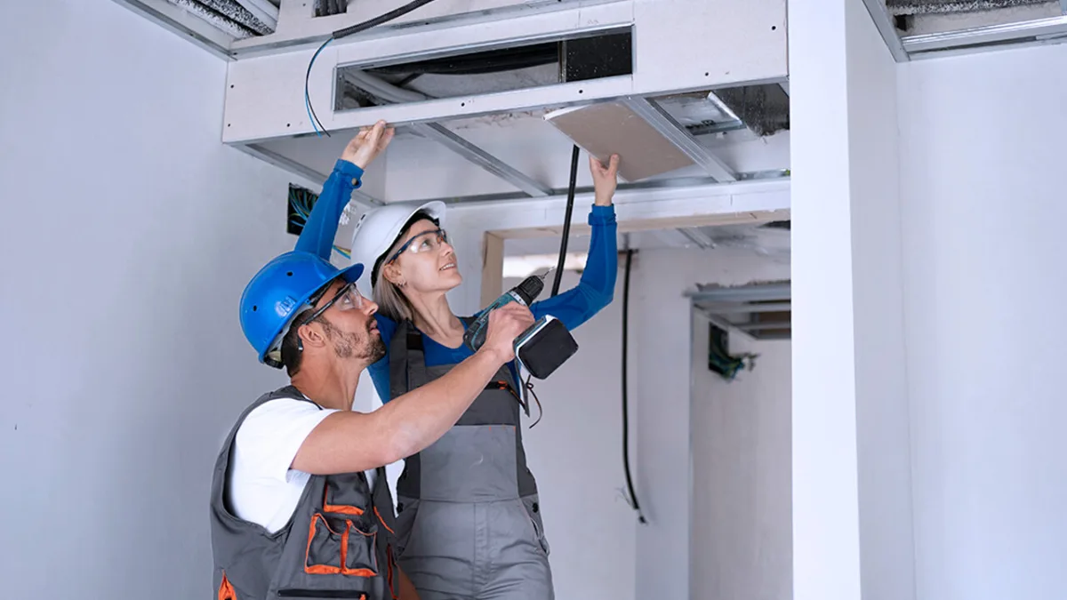 HVAC technicians inspecting air conditioning unit for maintenance on site