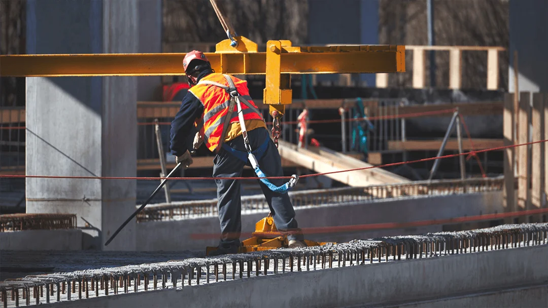 Construction worker with safety harness working at height on steel beam