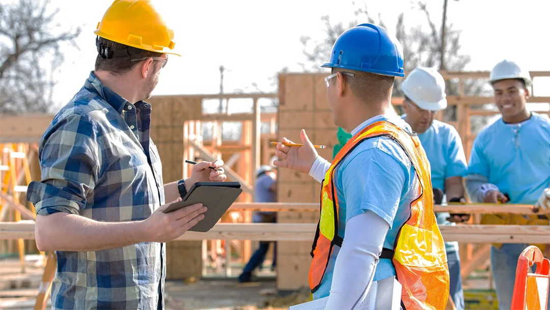 Construction supervisor conducting site inspection using tablet with team members