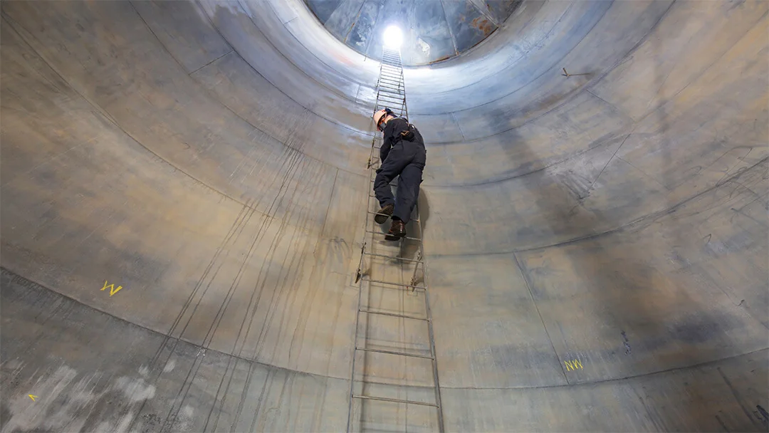 Confined space worker on fixed ladder inside storage silo