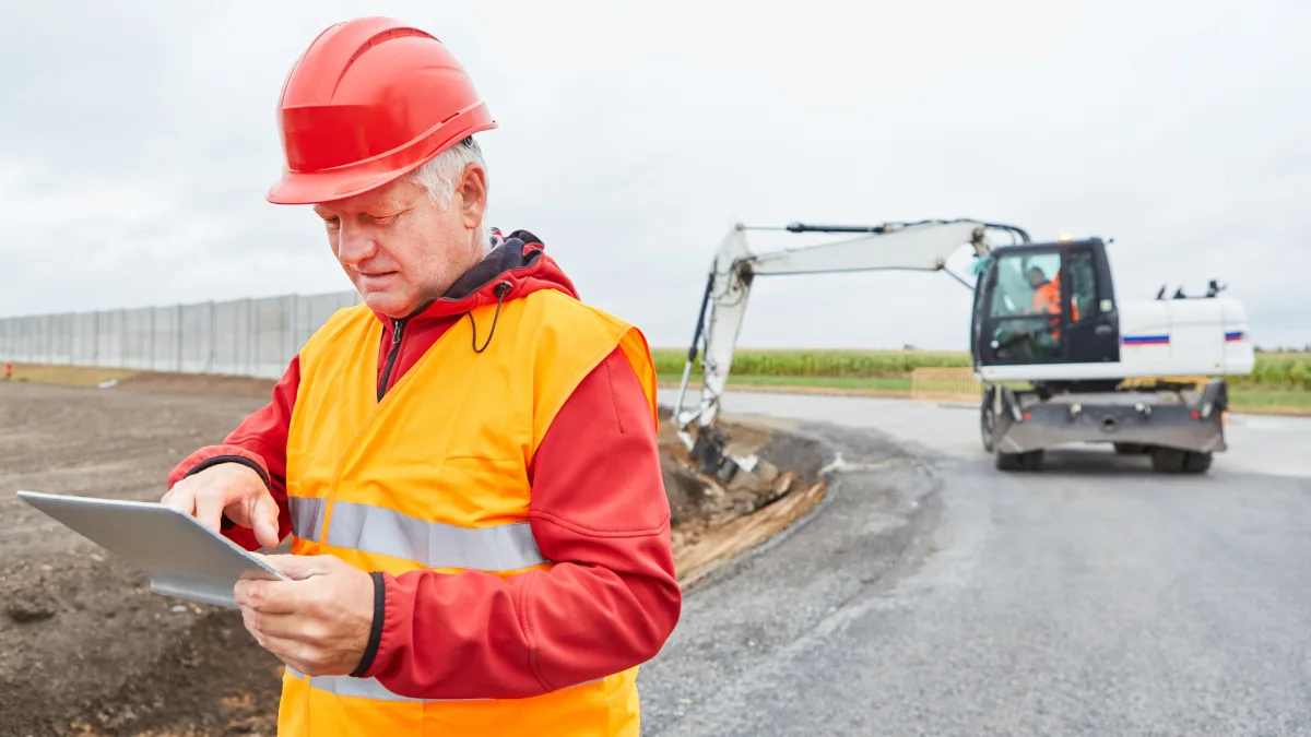 Construction supervisor reviewing site data on tablet at excavation site