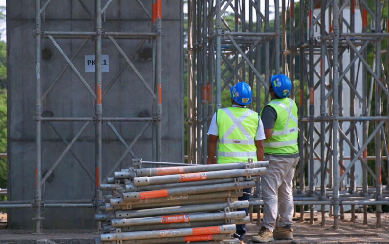 Construction workers monitoring materials and scaffolding on an active building site