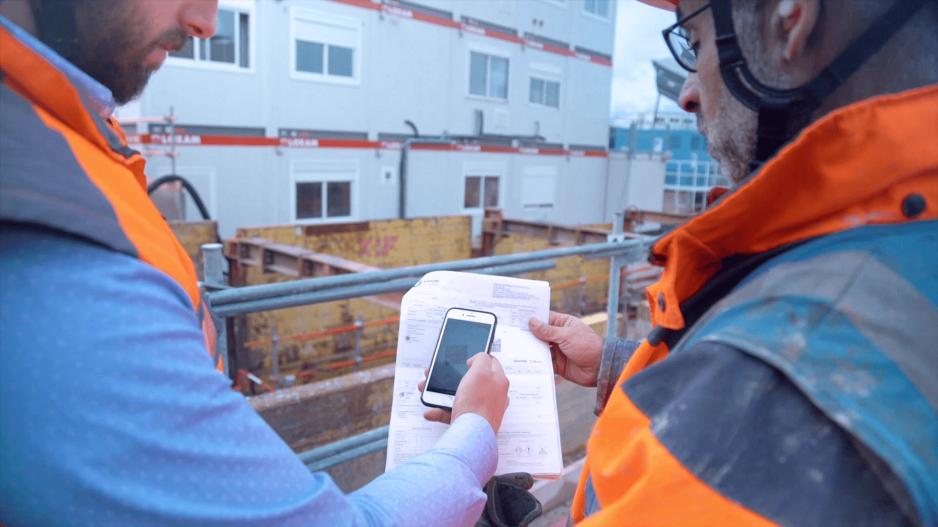 Construction workers reviewing site data on mobile device at job site