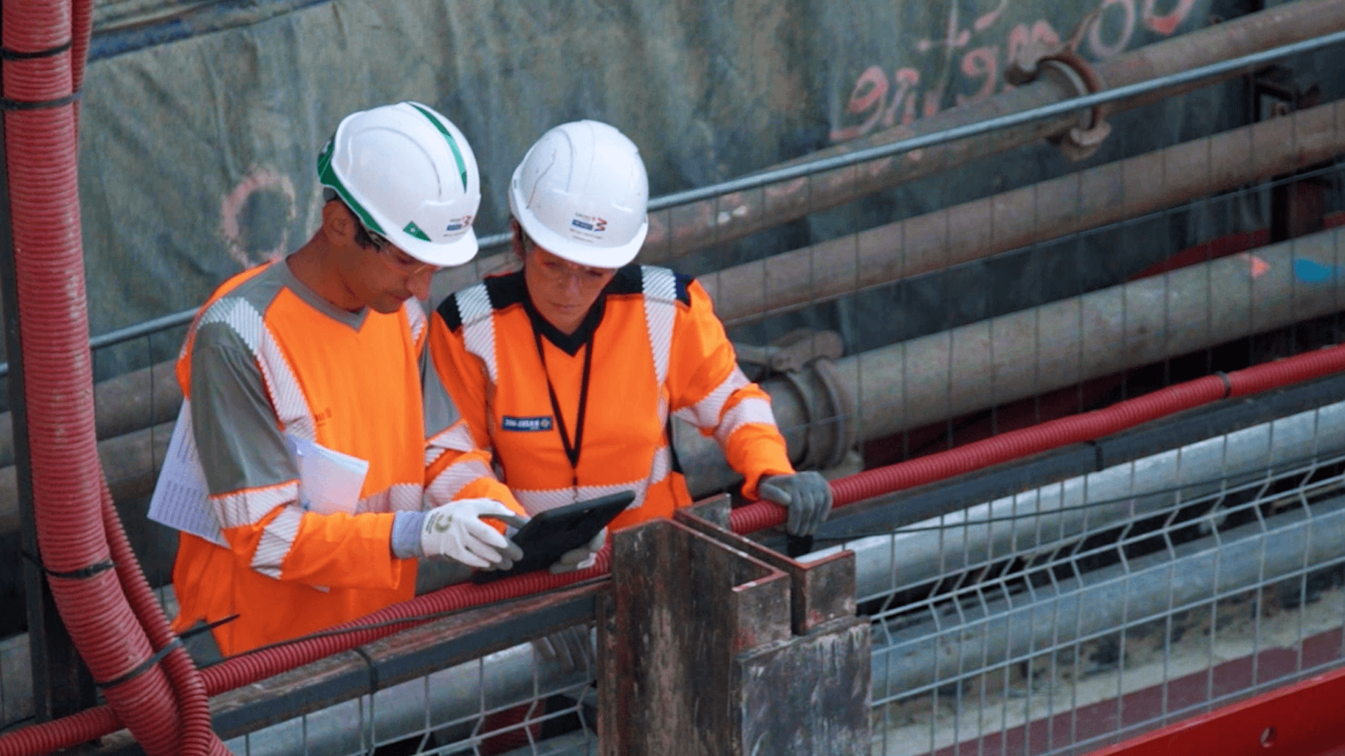 Two construction workers reviewing Novade site management app on tablet at Grand Paris Metro
