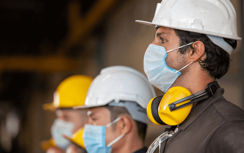 Construction workers with hard hats, protective masks, and ear protection