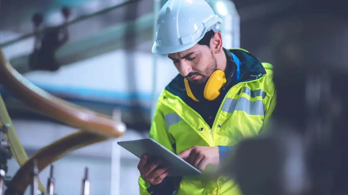 Site manager reviewing project data on tablet during industrial construction work