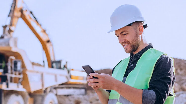 Mining site worker documenting inspection data on mobile device during excavation