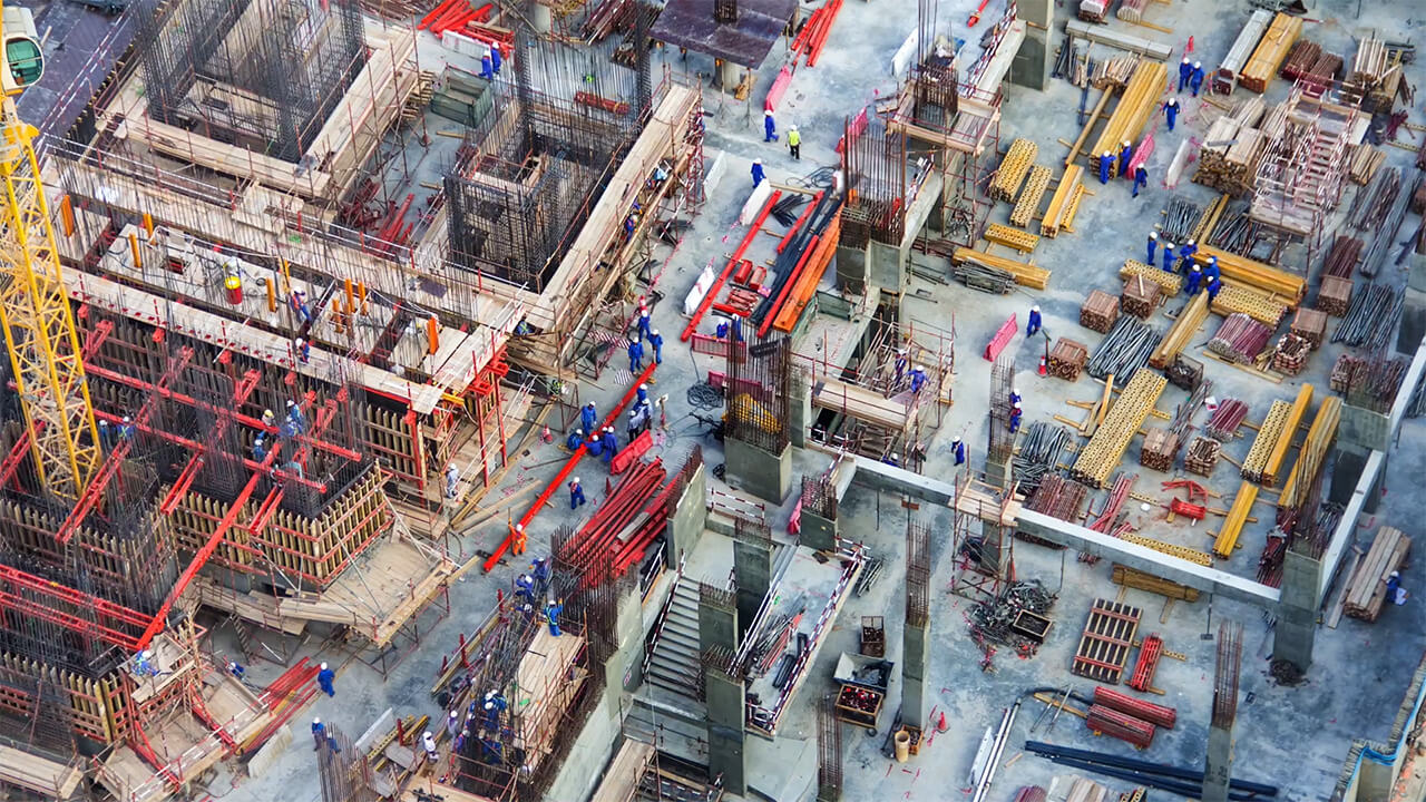 Aerial view of busy construction site with workers, cranes, and equipment