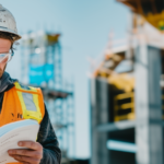 Construction compliance: worker reviewing blueprints on active job site